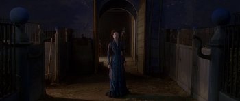 Movie still from “The Portrait of a Lady” (1996), directed by Jane Campion – A woman in a blue dress standing in an archway at night; Wide shot, Low angle