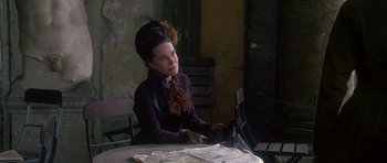 Movie still from “The Portrait of a Lady” (1996), directed by Jane Campion – A woman sitting at a table in a room; Medium shot, Over the shoulder angle