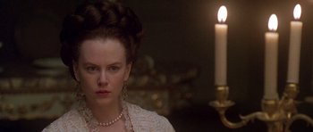 Movie still from “The Portrait of a Lady” (1996), directed by Jane Campion – A woman with a braid and a pearl necklace in front of a lit candle; Close Up shot, Over the shoulder angle