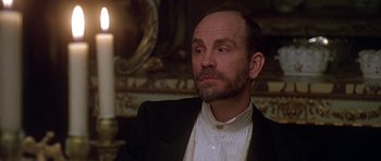Movie still from “The Portrait of a Lady” (1996), directed by Jane Campion – A man in a suit and a white shirt is sitting in front of a candle; Close Up shot, Over the shoulder angle