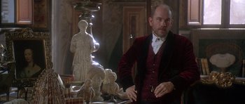Movie still from “The Portrait of a Lady” (1996), directed by Jane Campion – A man standing in front of a table with statues; Medium shot, Over the shoulder angle