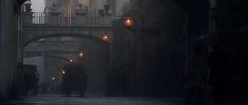 Movie still from “The Portrait of a Lady” (1996), directed by Jane Campion – A couple of people walking down a street with umbrellas; Extreme Wide shot, Over the shoulder angle
