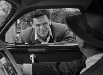 Movie still from “The Postman Always Rings Twice” (1946), directed by Tay Garnett – A man in a suit looking at another man in a hat; Medium shot, Over the shoulder angle