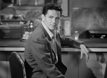 Movie still from “The Postman Always Rings Twice” (1946), directed by Tay Garnett – Black and white photograph of a man sitting at a counter; Medium shot, High angle