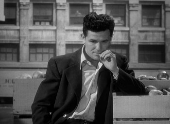 Movie still from “The Postman Always Rings Twice” (1946), directed by Tay Garnett – A black and white photo of a man in a suit and tie; Medium shot, High angle