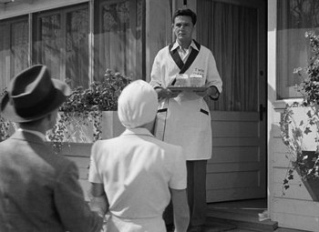 Movie still from “The Postman Always Rings Twice” (1946), directed by Tay Garnett – An old photo of a man holding a plate in front of two women; Medium shot, Over the shoulder angle
