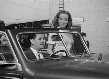 Movie still from “The Postman Always Rings Twice” (1946), directed by Tay Garnett – A man and a woman sitting in the driver's seat of a car; Medium shot, Low angle