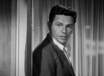 Movie still from “The Postman Always Rings Twice” (1946), directed by Tay Garnett – Black and white photograph of a man wearing a suit and tie; Close Up shot, Over the shoulder angle