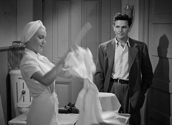 Movie still from “The Postman Always Rings Twice” (1946), directed by Tay Garnett – A man and a woman are washing dishes in a kitchen; Medium shot, Over the shoulder angle