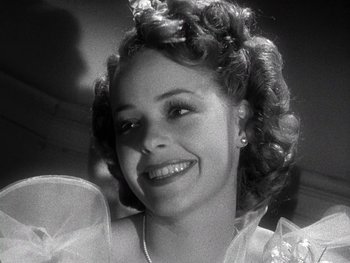 Movie still from “The Pride of the Yankees” (1942), directed by Sam Wood – A black and white photo of a woman smiling; Close Up shot, Low angle