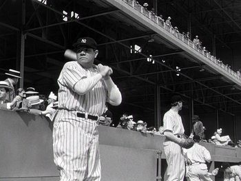 Movie still from “The Pride of the Yankees” (1942), directed by Sam Wood – A baseball player is holding a baseball bat in front of a group of people; Medium shot, Low angle