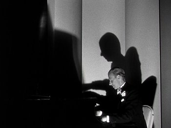 Movie still from “The Pride of the Yankees” (1942), directed by Sam Wood – A black and white photo of a man sitting at a piano; Medium shot, Low angle