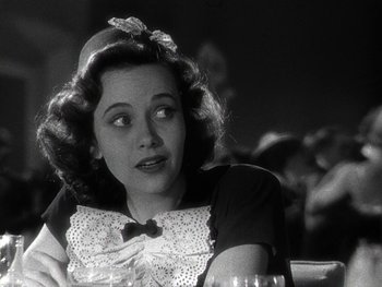 Movie still from “The Pride of the Yankees” (1942), directed by Sam Wood – A black and white photo of a woman sitting at a table; Close Up shot, Over the shoulder angle