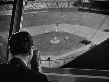 Movie still from “The Pride of the Yankees” (1942), directed by Sam Wood – A man is looking out of a window at a baseball game; Extreme Wide shot, High angle