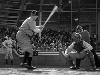 Movie still from “The Pride of the Yankees” (1942), directed by Sam Wood – A baseball player swinging a baseball bat at a game; Wide shot, Low angle