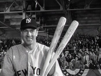 Movie still from “The Pride of the Yankees” (1942), directed by Sam Wood – A man holding two wooden baseball bats in front of a crowd; Medium shot, Low angle