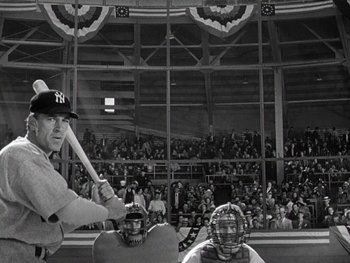 Movie still from “The Pride of the Yankees” (1942), directed by Sam Wood – A man holding a baseball bat in front of a crowd; Medium shot, Low angle