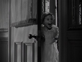 Movie still from “The Pride of the Yankees” (1942), directed by Sam Wood – A little girl in a white dress standing in front of a door; Medium shot, Over the shoulder angle