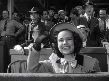Movie still from “The Pride of the Yankees” (1942), directed by Sam Wood – An old photo of a woman in a hat waving at the crowd; Medium shot, Low angle