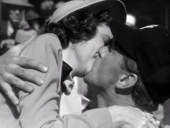 Movie still from “The Pride of the Yankees” (1942), directed by Sam Wood – A man and a woman kissing each other in front of a group of people; Close Up shot, Low angle