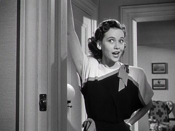 Movie still from “The Pride of the Yankees” (1942), directed by Sam Wood – A black - and - white photo of a woman standing in front of a door; Medium shot, Low angle