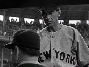 Movie still from “The Pride of the Yankees” (1942), directed by Sam Wood – A baseball player is talking to a man in the stands; Medium shot, Low angle