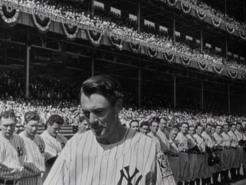 Movie still from “The Pride of the Yankees” (1942), directed by Sam Wood – A man in a baseball uniform standing in front of a group of people; Wide shot, Low angle