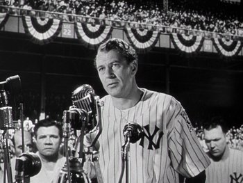 Movie still from “The Pride of the Yankees” (1942), directed by Sam Wood – A baseball player is speaking into a microphone at a baseball game; Medium shot, Low angle