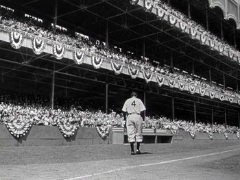 Movie still from “The Pride of the Yankees” (1942), directed by Sam Wood – A baseball player standing in front of a crowd of people; Extreme Wide shot, Low angle