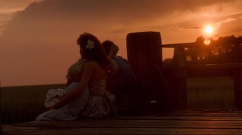 Movie still from “The Prince of Tides” (1991), directed by Barbra Streisand – Two people sitting on a dock watching the sunset; Wide shot, Low angle