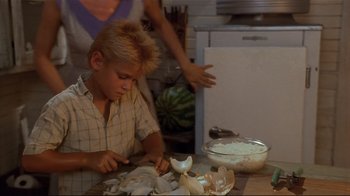 Movie still from “The Prince of Tides” (1991), directed by Barbra Streisand – A young boy is cutting mushrooms in a kitchen; Medium shot, High angle