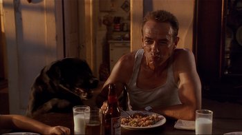 Movie still from “The Prince of Tides” (1991), directed by Barbra Streisand – A man sitting at a table with a plate of food; Medium shot, Low angle