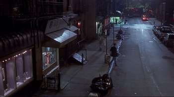 Movie still from “The Prince of Tides” (1991), directed by Barbra Streisand – A city street at night with people sitting on the sidewalk; Extreme Wide shot, High angle