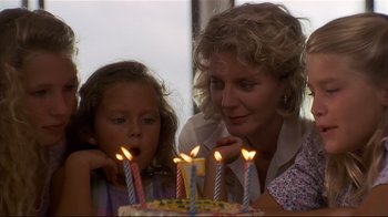 Movie still from “The Prince of Tides” (1991), directed by Barbra Streisand – A woman and a girl blow out candles on a cake; Close Up shot, Over the shoulder angle