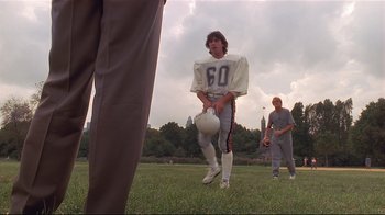 Movie still from “The Prince of Tides” (1991), directed by Barbra Streisand – A football player is standing in the grass with a helmet; Wide shot, Low angle