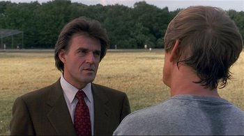 Movie still from “The Prince of Tides” (1991), directed by Barbra Streisand – A man wearing a suit and tie talking to another man in a field; Close Up shot, Over the shoulder angle