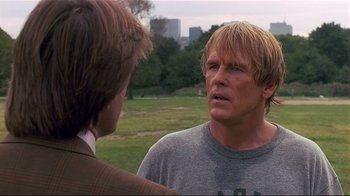 Movie still from “The Prince of Tides” (1991), directed by Barbra Streisand – A man in a gray t - shirt talking to another man in a brown suit; Close Up shot, Over the shoulder angle