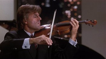 Movie still from “The Prince of Tides” (1991), directed by Barbra Streisand – A man in a suit and tie playing the violin; Close Up shot, Low angle