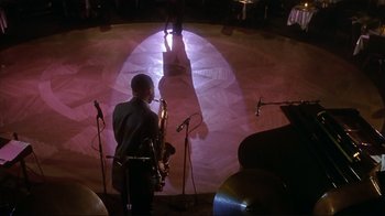 Movie still from “The Prince of Tides” (1991), directed by Barbra Streisand – A man standing in front of microphones holding a saxophone; Extreme Wide shot, High angle