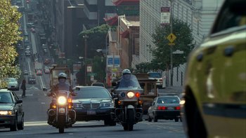 Movie still from “The Princess Diaries” (2001), directed by Garry Marshall – A group of people on motorcycles driving down a street; Extreme Wide shot, Over the shoulder angle