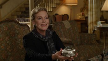 Movie still from “The Princess Diaries” (2001), directed by Garry Marshall – A woman sitting on a couch holding a silver bowl; Medium shot, Over the shoulder angle