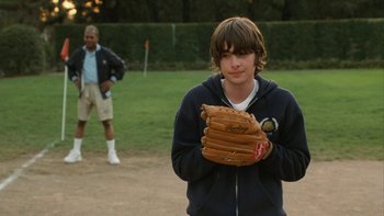 Movie still from “The Princess Diaries” (2001), directed by Garry Marshall – A young man holding a catchers mitt on a baseball field; Medium shot, Over the shoulder angle