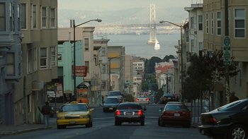 Movie still from “The Princess Diaries” (2001), directed by Garry Marshall – Cars driving down a street with a bridge in the background; Extreme Wide shot, Low angle