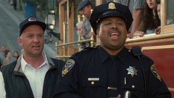 Movie still from “The Princess Diaries” (2001), directed by Garry Marshall – A man in a police officer's uniform laughing; Medium shot, Over the shoulder angle
