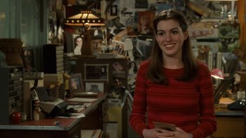 Movie still from “The Princess Diaries” (2001), directed by Garry Marshall – A woman standing in front of a wall covered in pictures; Medium shot, Over the shoulder angle