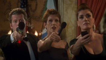 Movie still from “The Princess Diaries” (2001), directed by Garry Marshall – A woman holding a microphone in front of two other people; Medium shot, Over the shoulder angle