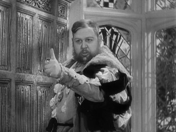 Movie still from “The Private Life of Henry VIII” (1933), directed by Alexander Korda – A man dressed as a medieval knight points to the camera; Medium shot, Over the shoulder angle