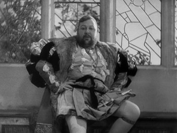 Movie still from “The Private Life of Henry VIII” (1933), directed by Alexander Korda – A man sitting on top of a bench wearing a robe; Medium shot, Low angle