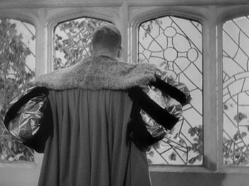 Movie still from “The Private Life of Henry VIII” (1933), directed by Alexander Korda – A man wearing a fur coat standing in front of stained glass windows; Medium shot, Low angle