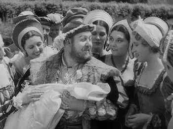 Movie still from “The Private Life of Henry VIII” (1933), directed by Alexander Korda – An old photo of a group of people holding a baby; Medium shot, High angle